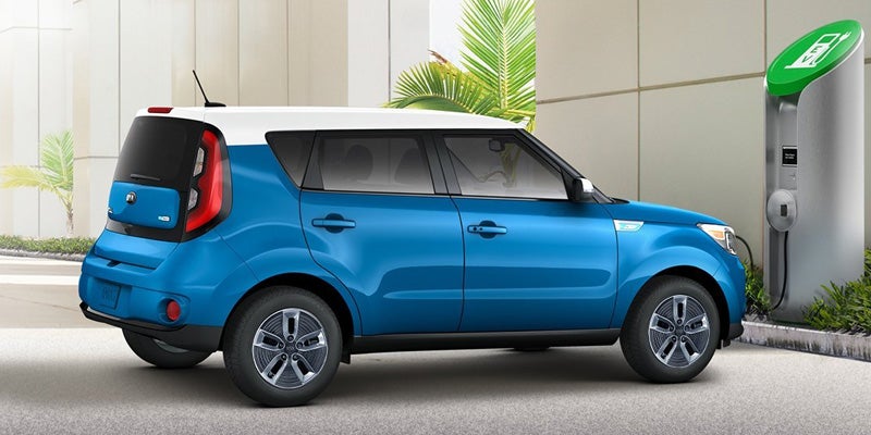 Blue Kia Soul electric vehicle charging at a wall-mounted EV charger