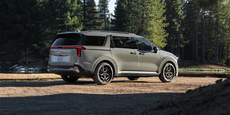 Shows a single silver SUV parked on a dirt road in a forested outdoor setting