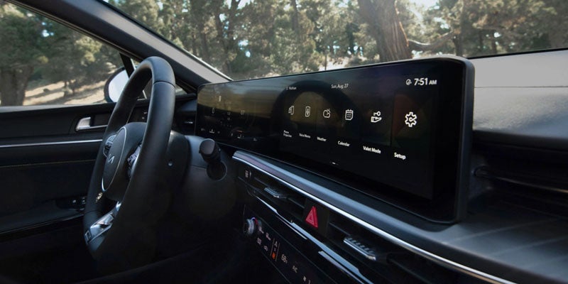 A car's interior with a large, sleek digital display for navigation and controls, visible from the driver's seat.