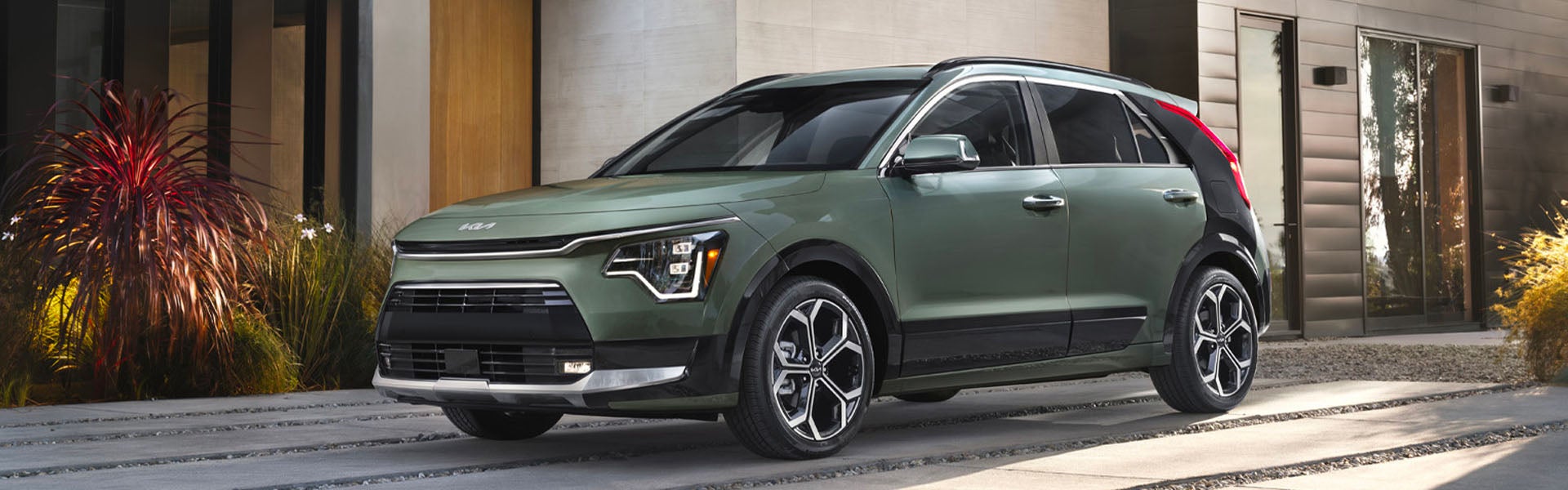 crossover parked on a modern driveway with a dark grey and wood-paneled building in the background.