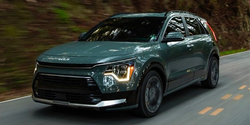 Kia SUV driving on road with headlights on