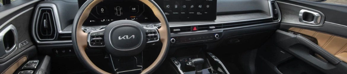 Interior view of a modern car with a two-tone steering wheel, digital dashboard, and brown accents on the door panels.