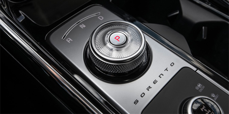 Close-up of a Kia Sorento's gear shift dial, showing the "P" engaged, drive modes, and other buttons.