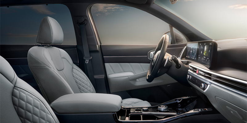 Interior of a car with light gray leather seats, modern dashboard, and large digital displays.