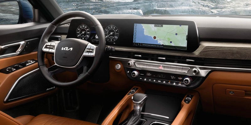 The modern brown and black interior of a car with a digital dashboard and central infotainment screen displaying a map.