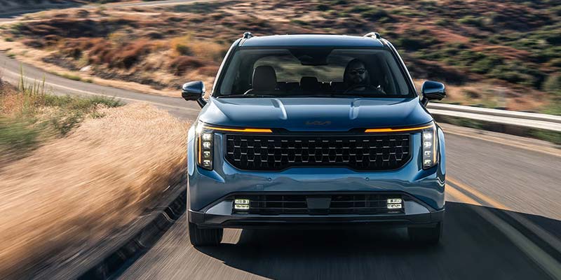 SUV drives down a paved road with a desert landscape in the background.