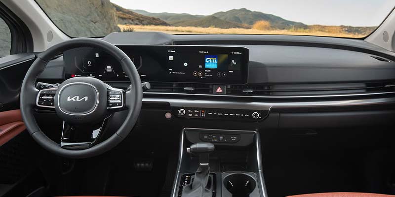 The dashboard of a Kia Carnival displays navigation and music on its large touchscreen.