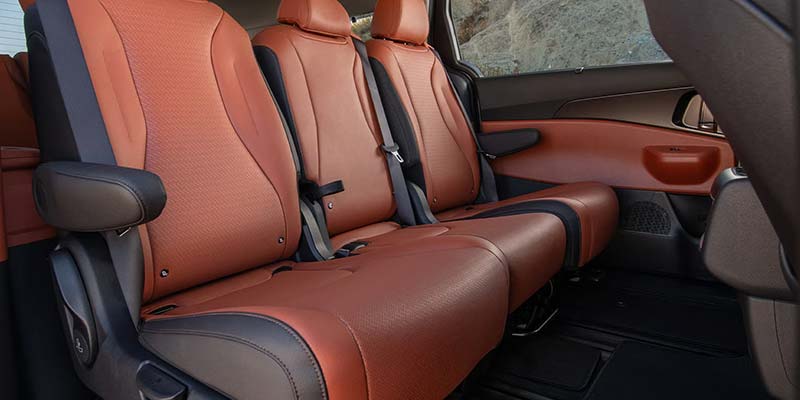 Tan leather seats fill the interior of a minivan, displaying ample space and passenger safety features.
