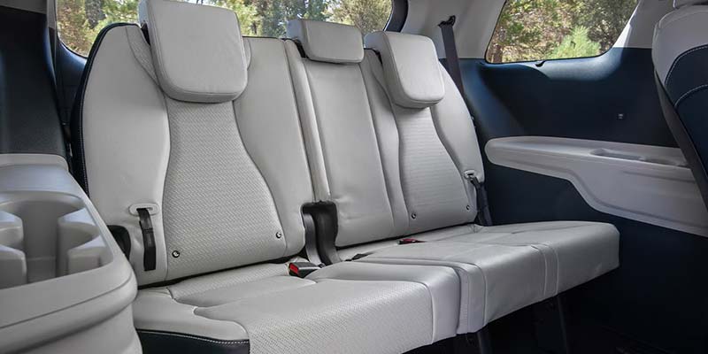 The interior of a vehicle shows the second and third row light gray leather seats with headrests and black accents.