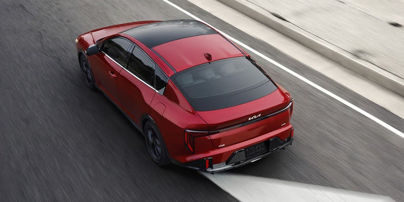 Kia K4 sedan top rear angle driving on highway