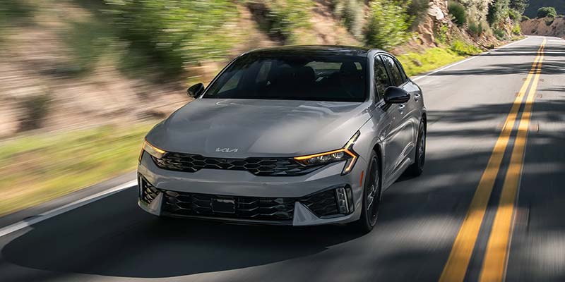 Front view of Kia K5 driving on scenic road
