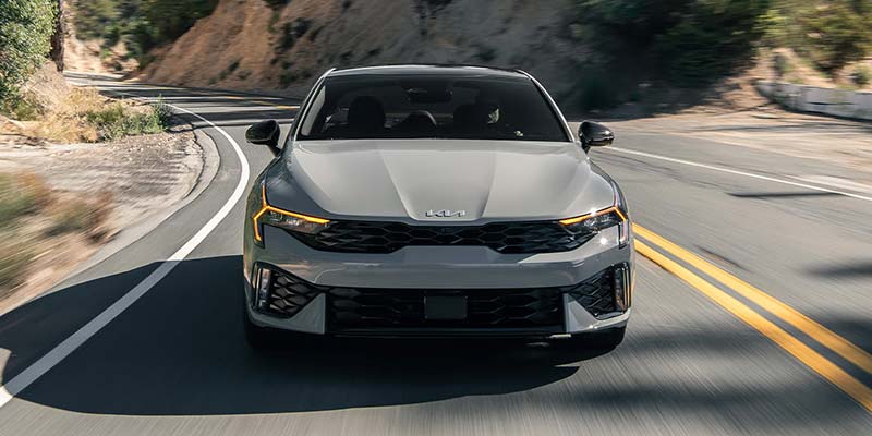 Front angle view of Kia K5 sedan driving on curved road
