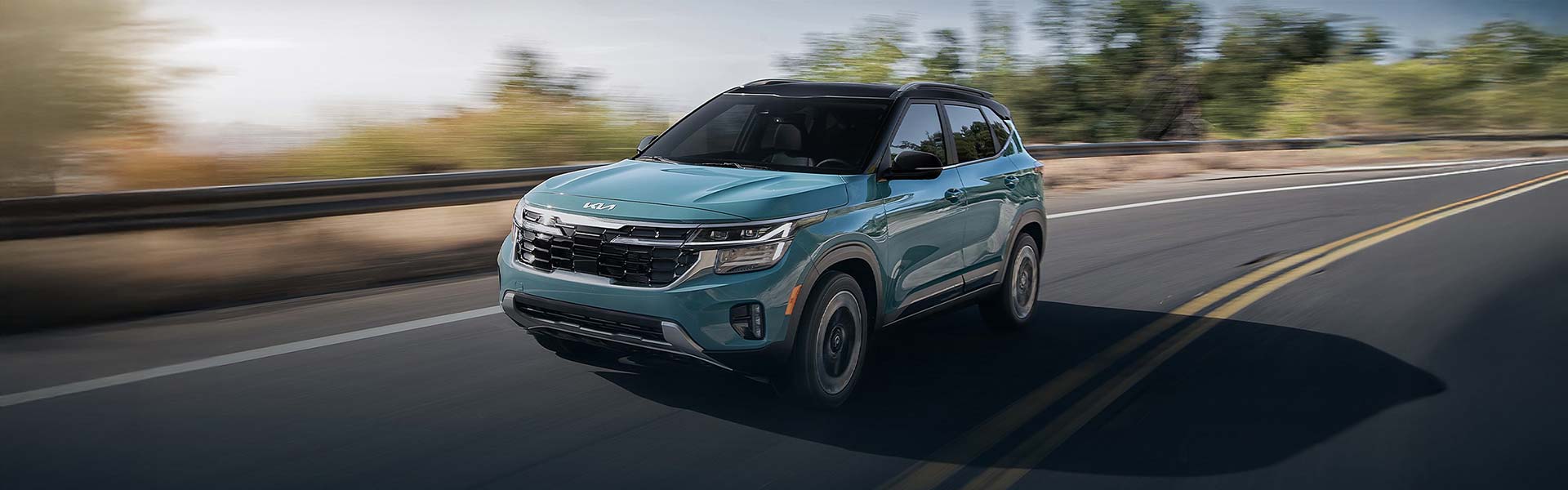 Kia Seltos driving quickly on a highway with blurred green trees in the background.