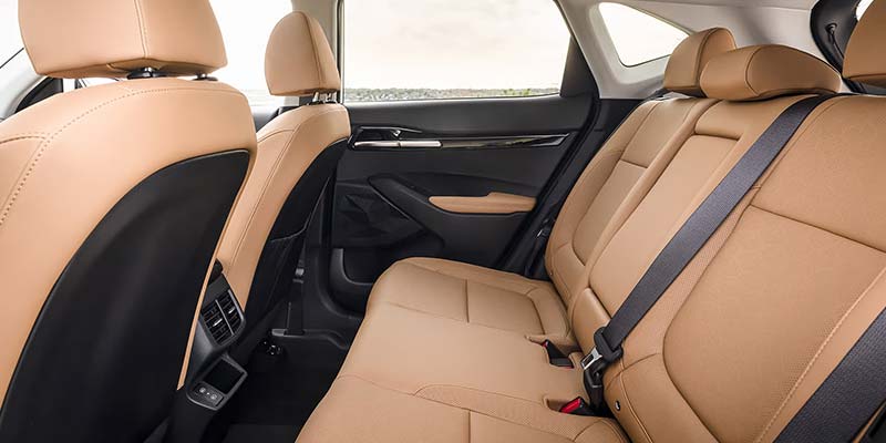 Interior view of a car with tan leather seats and dark gray door panels, showing front seat backs and rear seats.