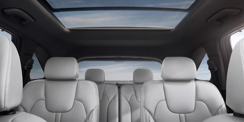 Interior of a car showing light gray seats, a large sunroof, and rear window.