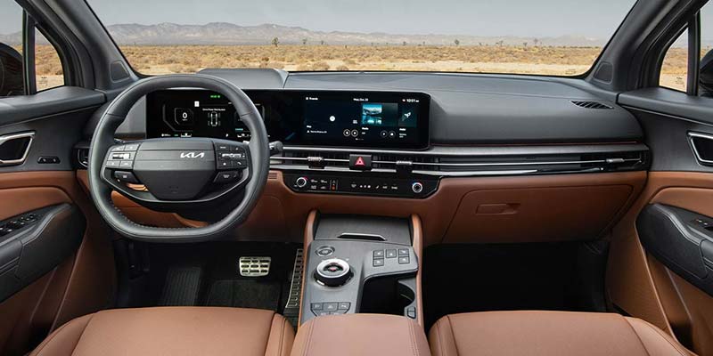 Interior view of a modern car dashboard with a digital display, steering wheel, and brown leather accents.