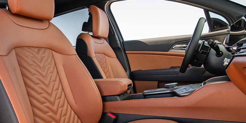 Brown and black car interior with patterned leather seats, door, and center console.